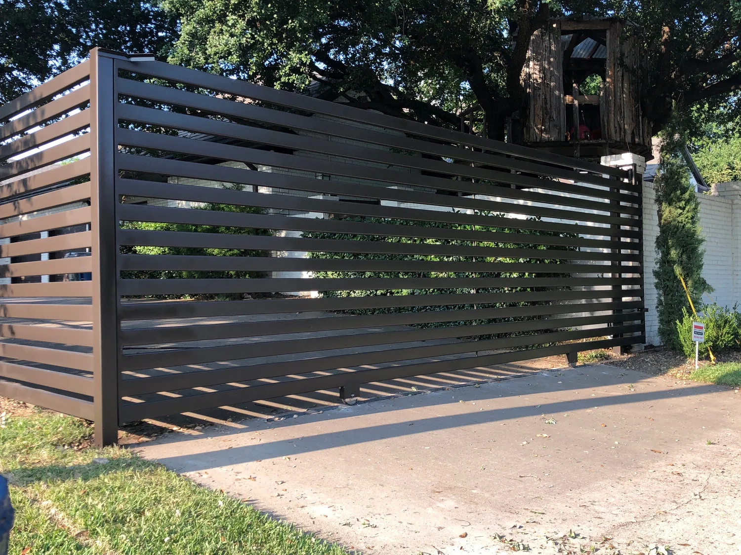Metal driveway gate with an intercom post