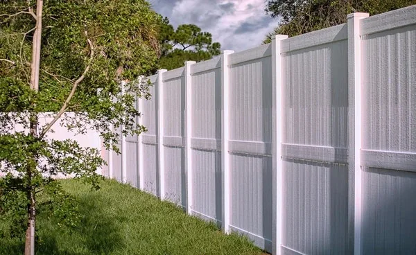 Tan vinyl fence running along a driveway